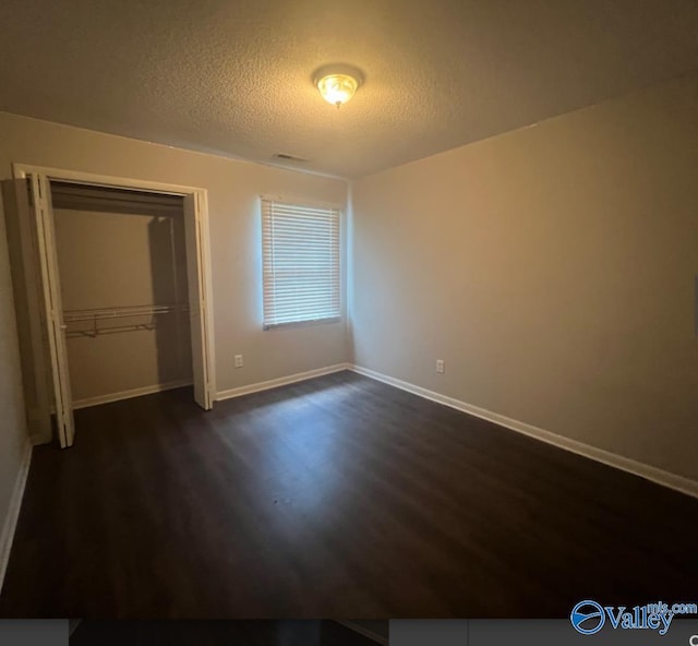 1008 Brighton Cir, Huntsville, AL 35803 - unfurnished bedroom with dark wood finished floors, a textured ceiling, baseboards, and a closet