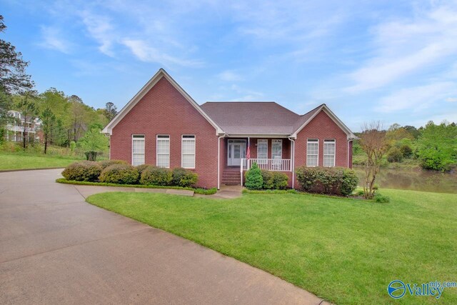 ranch-style house with a front yard, driveway, covered porch, and brick siding