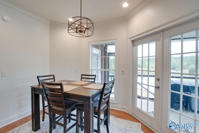 dining area featuring light wood-type flooring, ornamental molding, and an inviting chandelier