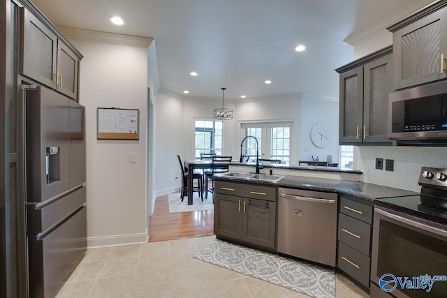kitchen with dark stone counters, tasteful backsplash, a sink, stainless steel appliances, and ornamental molding