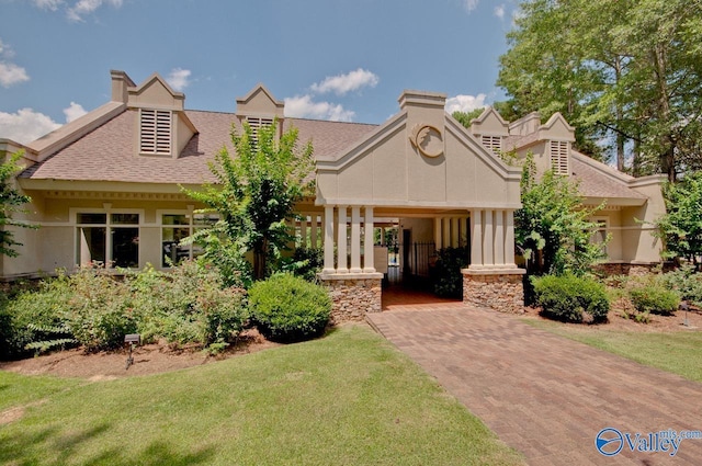view of front of house with a front yard, a shingled roof, and stucco siding