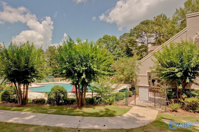 view of property's community with a gate, fence, and a swimming pool