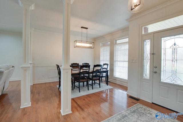 entryway with visible vents, light wood-type flooring, ornamental molding, and decorative columns