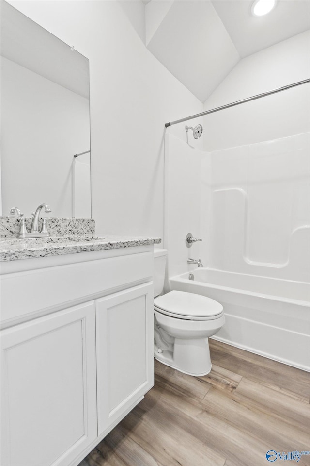 full bathroom featuring shower / bathing tub combination, vanity, vaulted ceiling, hardwood / wood-style flooring, and toilet