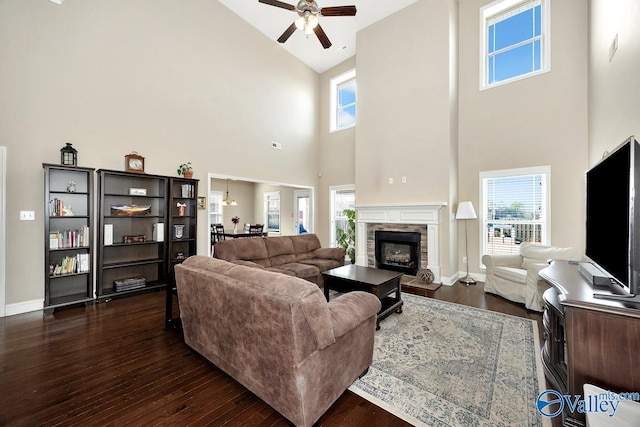 living room with plenty of natural light, dark wood finished floors, a stone fireplace, and baseboards