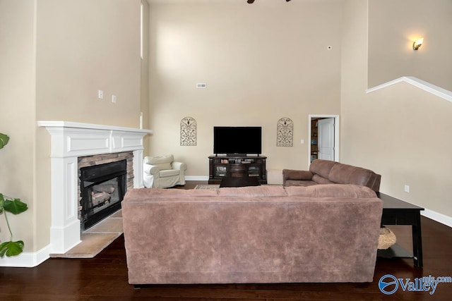 living area with a high ceiling, a fireplace, baseboards, and dark wood finished floors