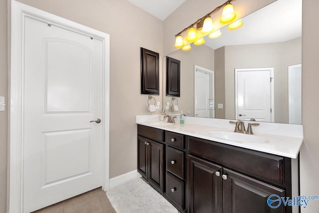 full bath featuring double vanity, tile patterned flooring, baseboards, and a sink