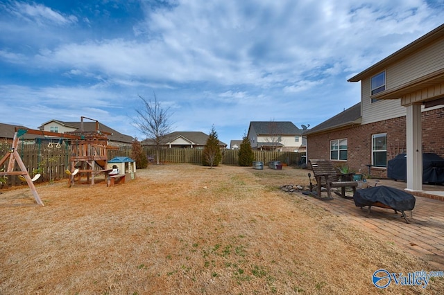 view of yard featuring a patio area, a playground, and a fenced backyard