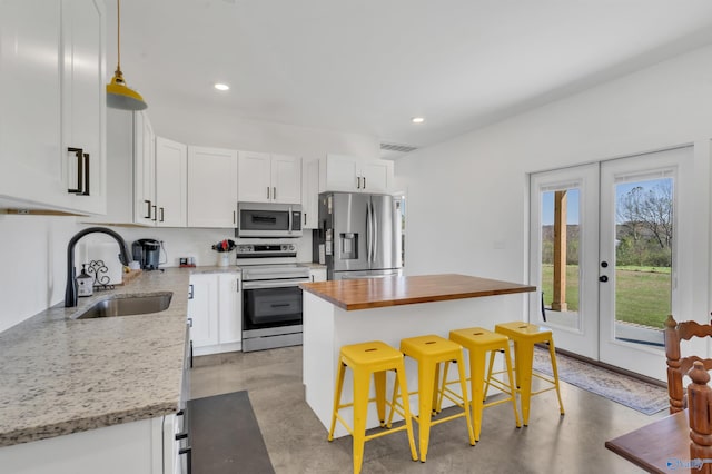 kitchen with a center island, sink, a kitchen bar, white cabinetry, and stainless steel appliances