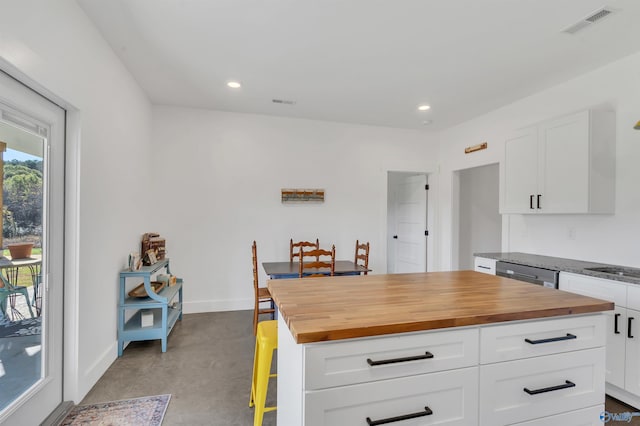 kitchen featuring wood counters, a kitchen island, white cabinetry, and dishwasher