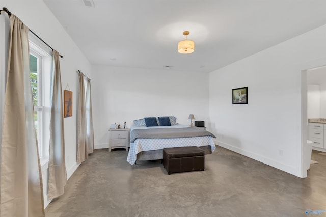 bedroom featuring connected bathroom and concrete flooring