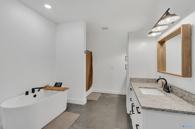 bathroom with a washtub, vanity, and concrete floors