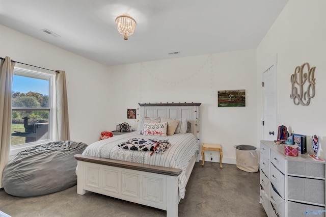 bedroom with concrete flooring and an inviting chandelier