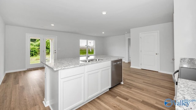 kitchen with light stone countertops, stainless steel dishwasher, a kitchen island with sink, white cabinetry, and sink