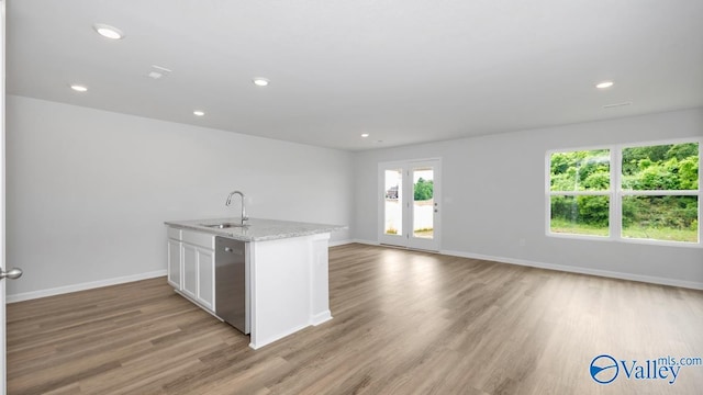 kitchen featuring light stone counters, dishwasher, light hardwood / wood-style floors, white cabinetry, and sink