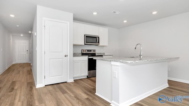 kitchen with stainless steel appliances, a center island with sink, white cabinets, and sink