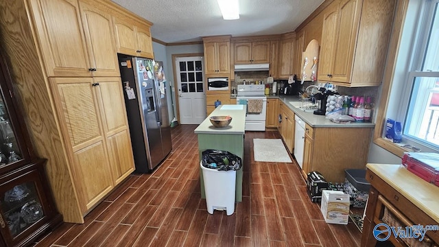 kitchen with wood tiled floor, a kitchen island, a sink, white appliances, and under cabinet range hood