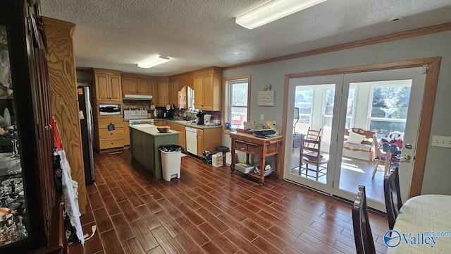 kitchen featuring wood finish floors, white appliances, a kitchen island, and under cabinet range hood