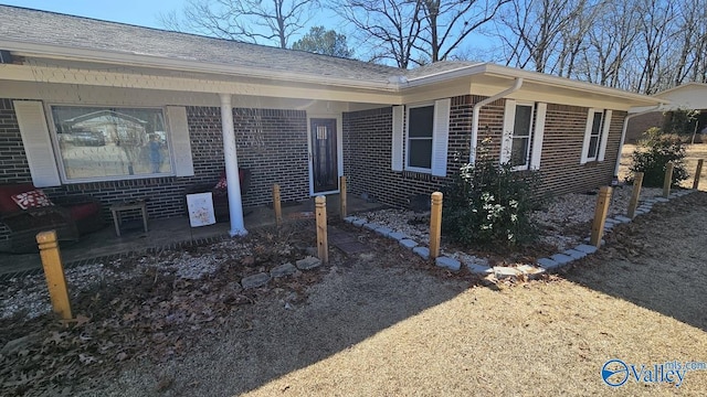 view of side of home with roof with shingles and brick siding