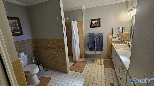 bathroom featuring toilet, curtained shower, crown molding, vanity, and tile walls