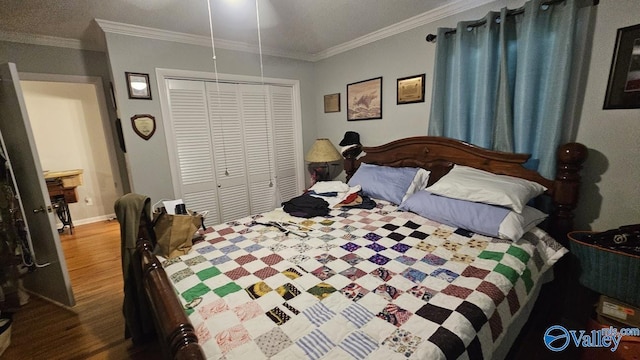 bedroom featuring crown molding, a closet, baseboards, and wood finished floors