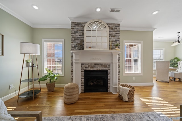 living room with a brick fireplace, plenty of natural light, hardwood / wood-style flooring, and crown molding