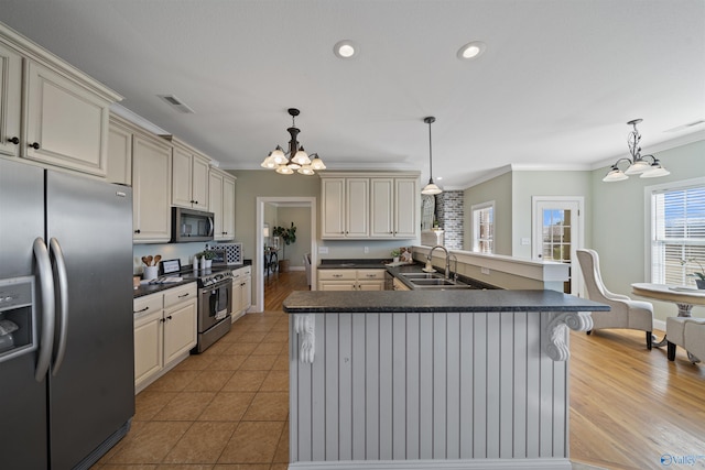 kitchen with decorative light fixtures, sink, stainless steel appliances, and cream cabinets