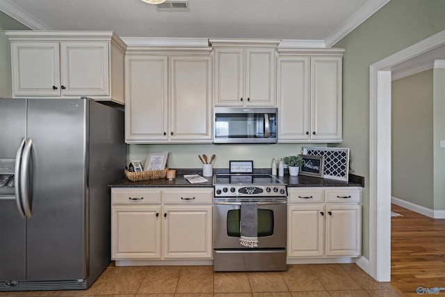 kitchen with light tile patterned floors, appliances with stainless steel finishes, and ornamental molding