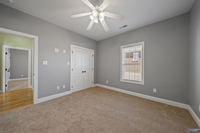 unfurnished bedroom with ceiling fan, light colored carpet, and a closet