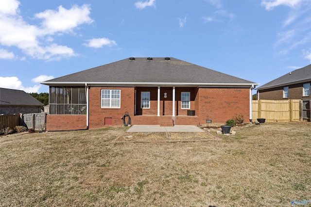 rear view of property featuring a patio area, a sunroom, and a lawn