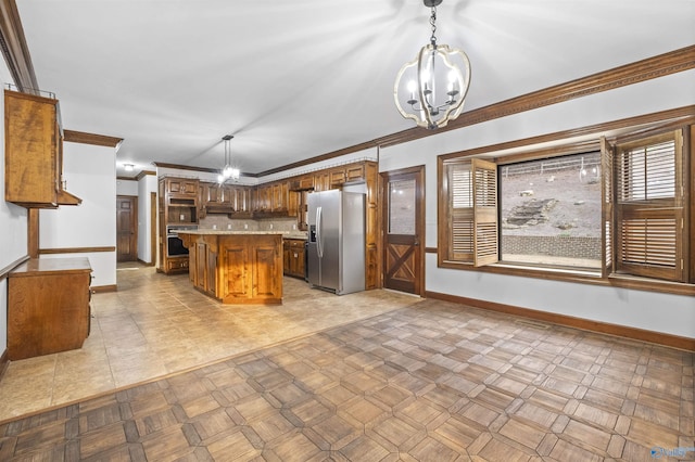 kitchen featuring light countertops, crown molding, an inviting chandelier, appliances with stainless steel finishes, and brown cabinetry