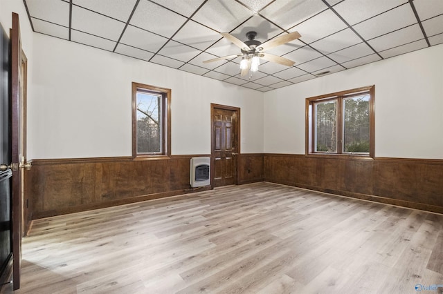 unfurnished room featuring a wainscoted wall, wood finished floors, heating unit, and a paneled ceiling