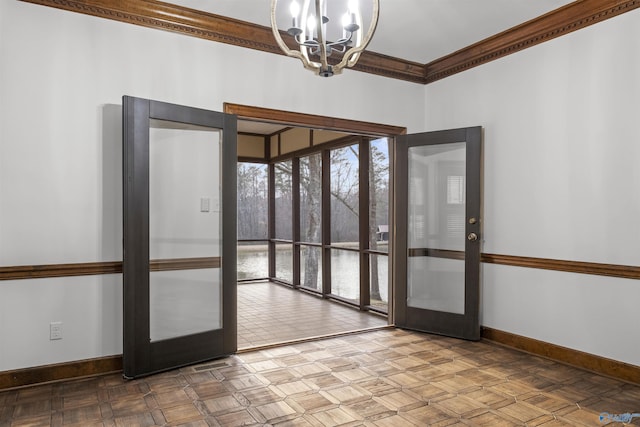 empty room with baseboards, french doors, an inviting chandelier, and crown molding