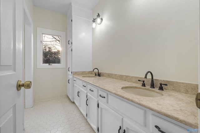 full bathroom with double vanity, a sink, tile patterned floors, and baseboards
