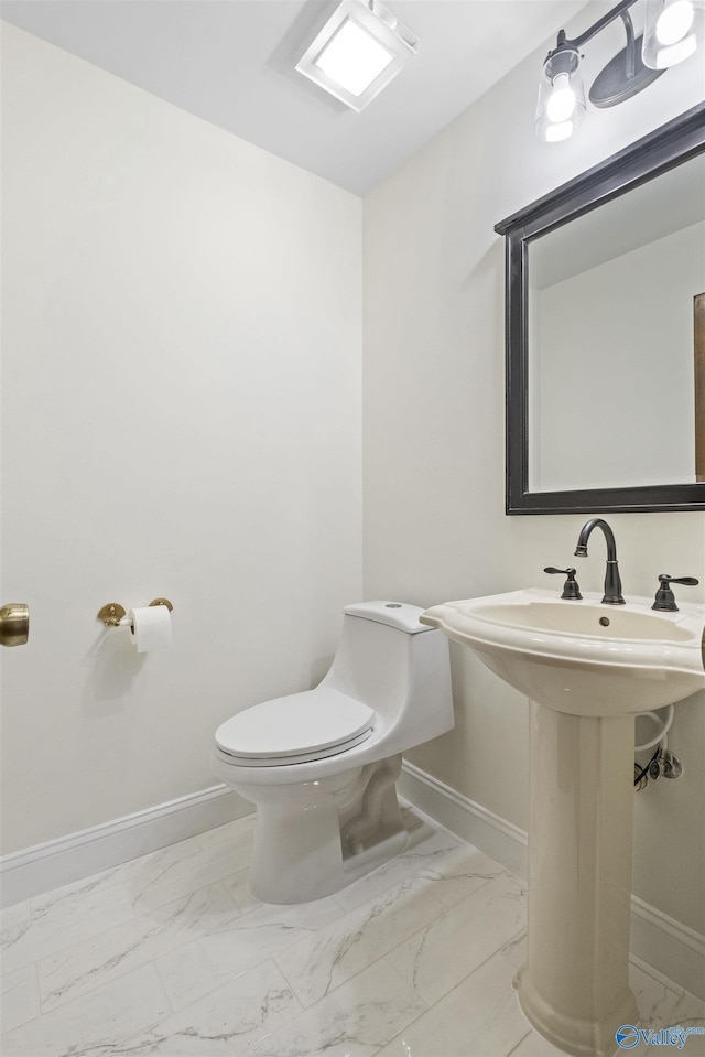 half bath with marble finish floor, baseboards, and toilet