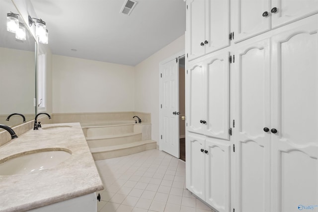 bathroom with tile patterned floors, a sink, a garden tub, and visible vents