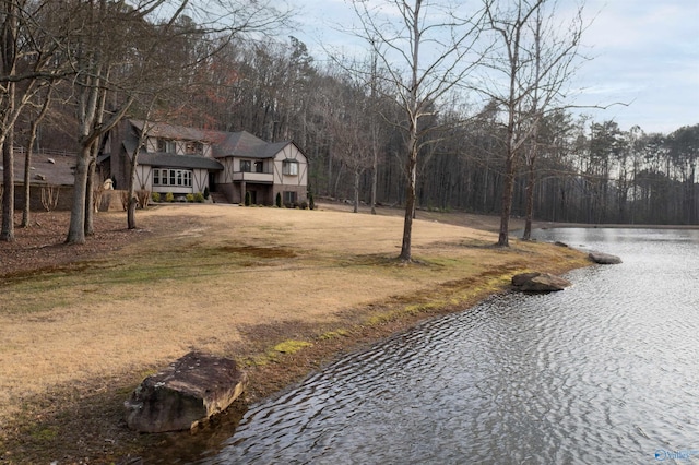 view of street with driveway, a water view, and a wooded view