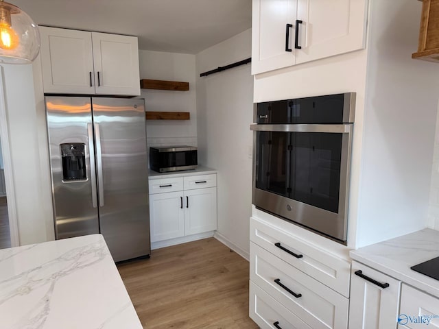 kitchen with pendant lighting, light wood-type flooring, stainless steel appliances, and white cabinetry