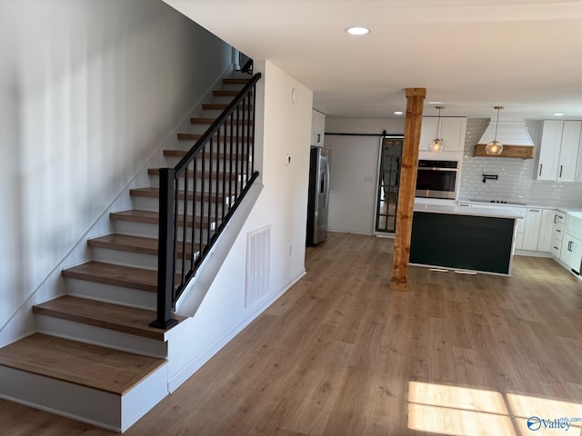 stairway featuring a barn door and hardwood / wood-style flooring