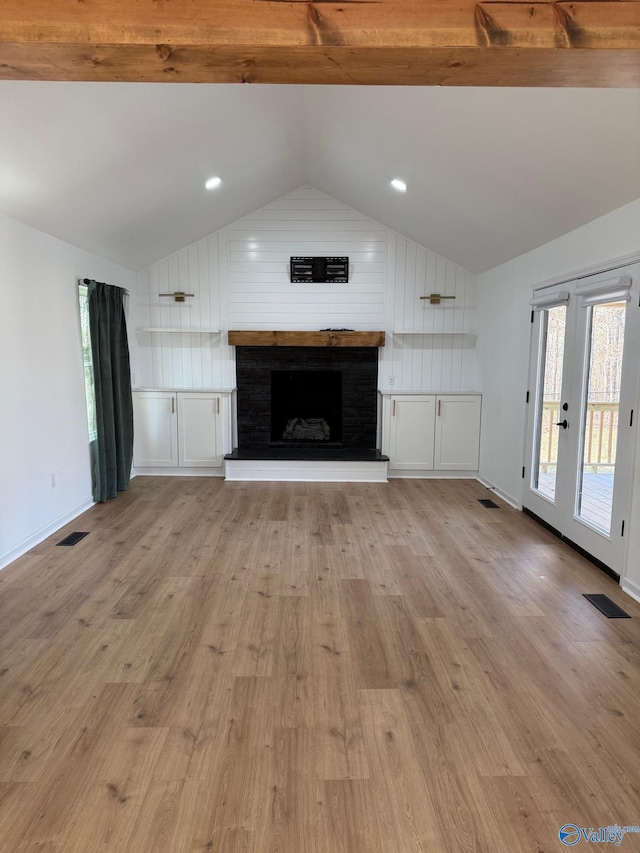 unfurnished living room with french doors, lofted ceiling, light hardwood / wood-style flooring, and a brick fireplace