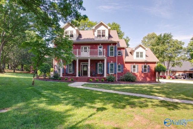 colonial-style house featuring covered porch, brick siding, a balcony, and a front lawn
