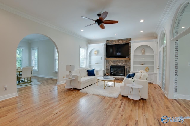 living room with a ceiling fan, light wood finished floors, a wealth of natural light, and a fireplace