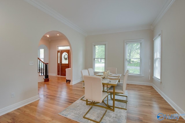 dining space featuring arched walkways, a wealth of natural light, and ornamental molding