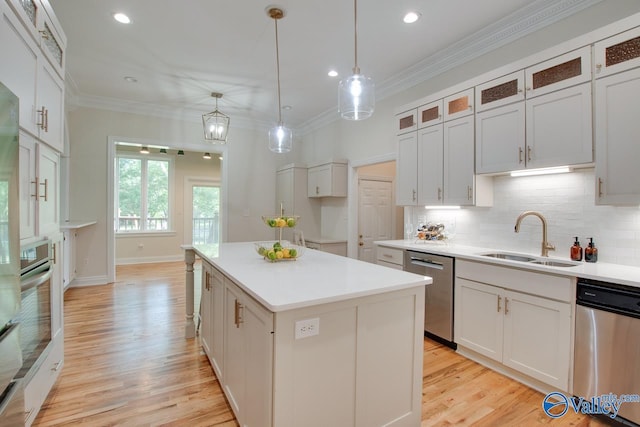 kitchen with decorative backsplash, a center island, a sink, light wood finished floors, and appliances with stainless steel finishes