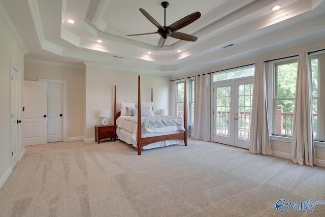 bedroom with light colored carpet, a tray ceiling, multiple windows, and french doors