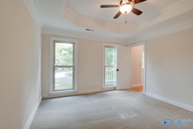 unfurnished room with crown molding, a tray ceiling, visible vents, and plenty of natural light
