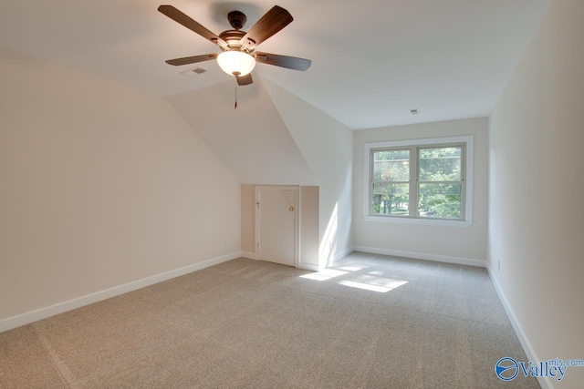 additional living space with a ceiling fan, visible vents, light colored carpet, vaulted ceiling, and baseboards