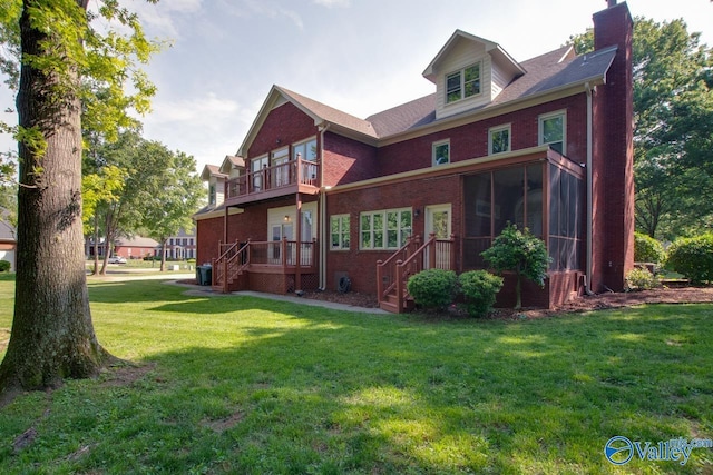 rear view of property featuring a balcony, a chimney, a sunroom, brick siding, and a lawn