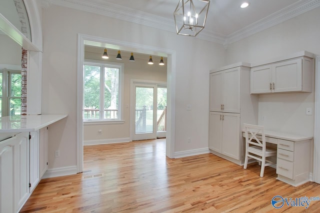 home office with visible vents, ornamental molding, an inviting chandelier, built in desk, and light wood-style flooring