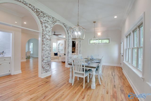 dining area featuring light wood-style floors, arched walkways, ornamental molding, and baseboards
